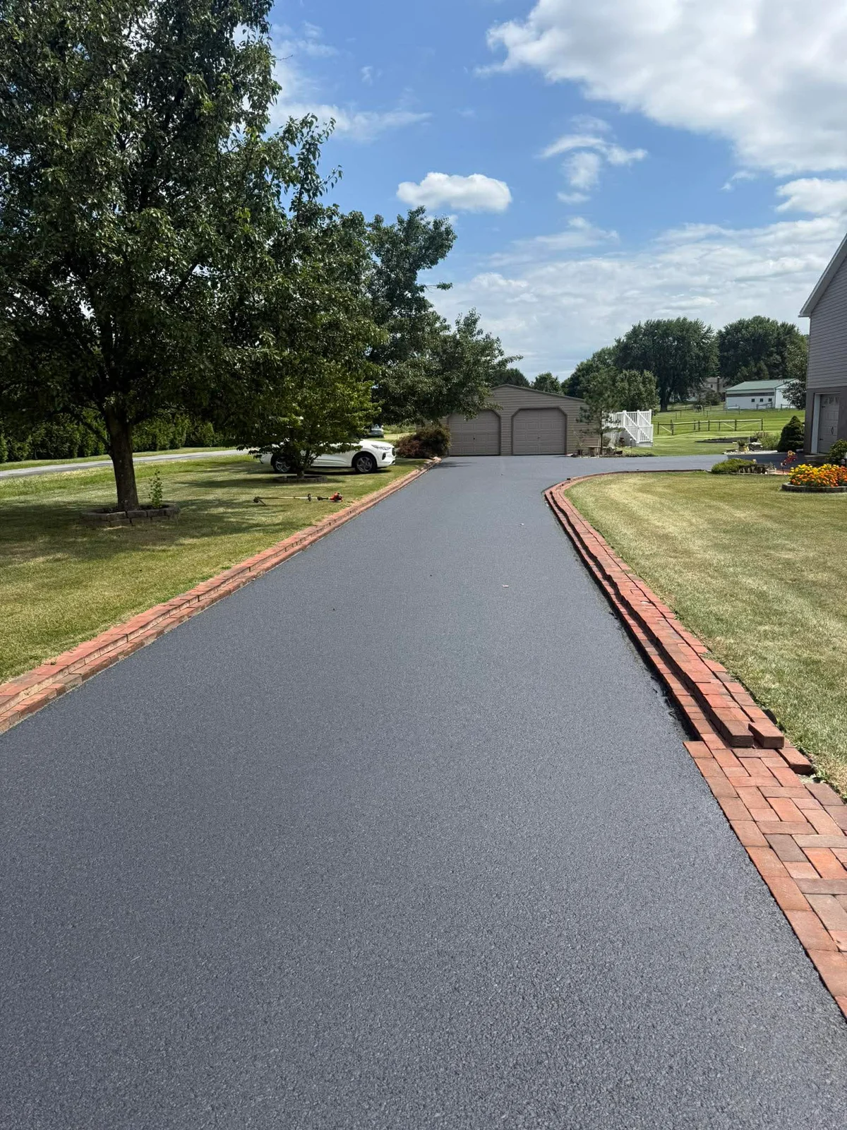 Restored driveway with fresh dark sealcoated finish